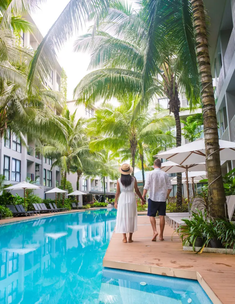 Couple walking beside a tropical resort pool for a luxury travel guide about planning premium vacations